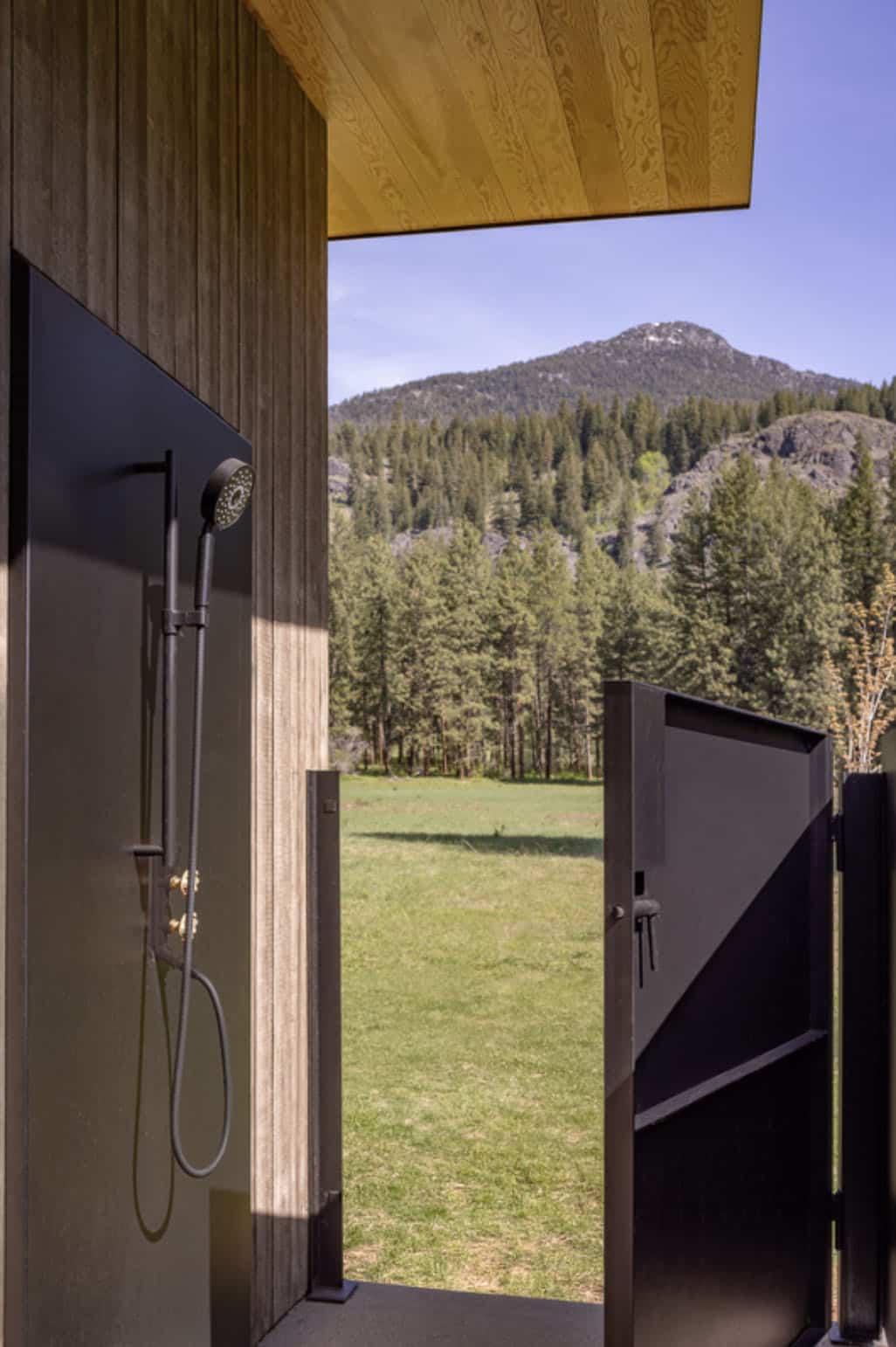 Outdoor shower with mountain view through open steel gate