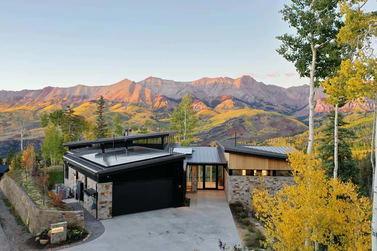 Modern mountain home with stone and black siding at dusk