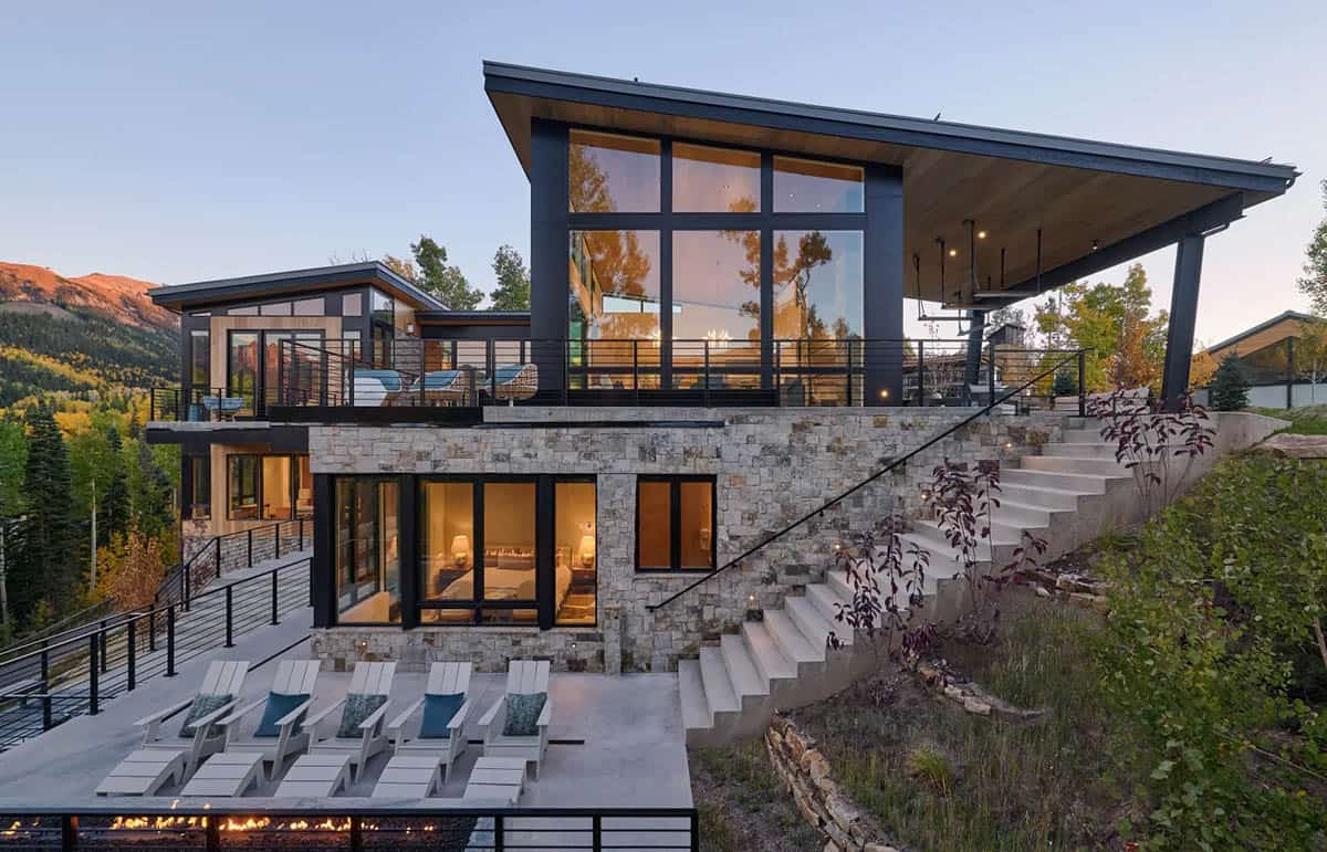 Stone terrace with lounge chairs overlooking a fire pit at dusk