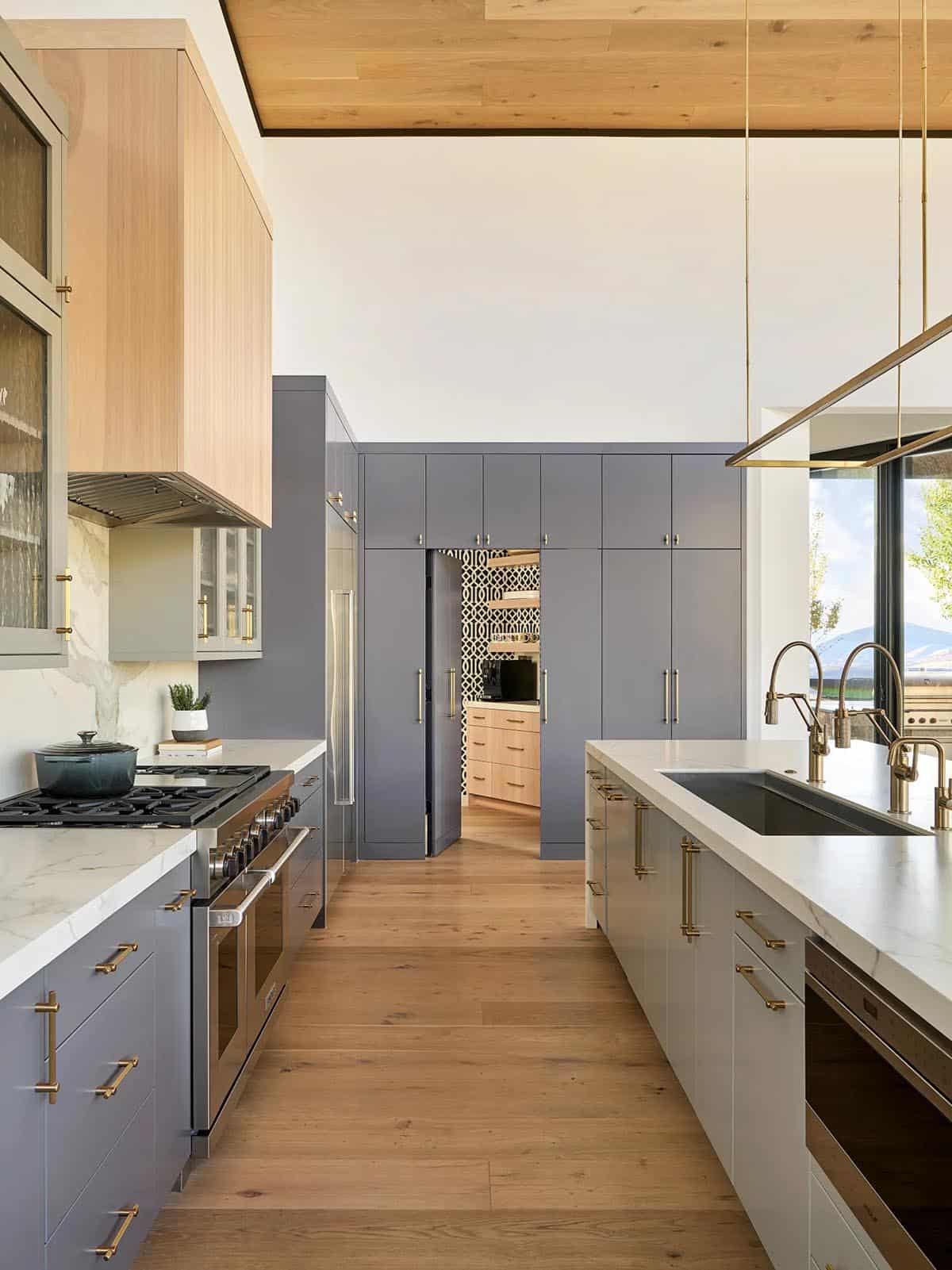 Galley kitchen view toward a hidden pantry with patterned wallpaper