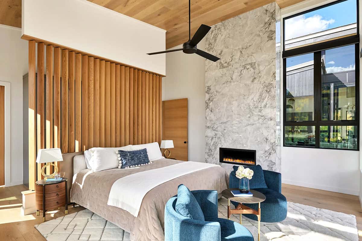 Bedroom with vertical wood slat headboard and marble fireplace wall
