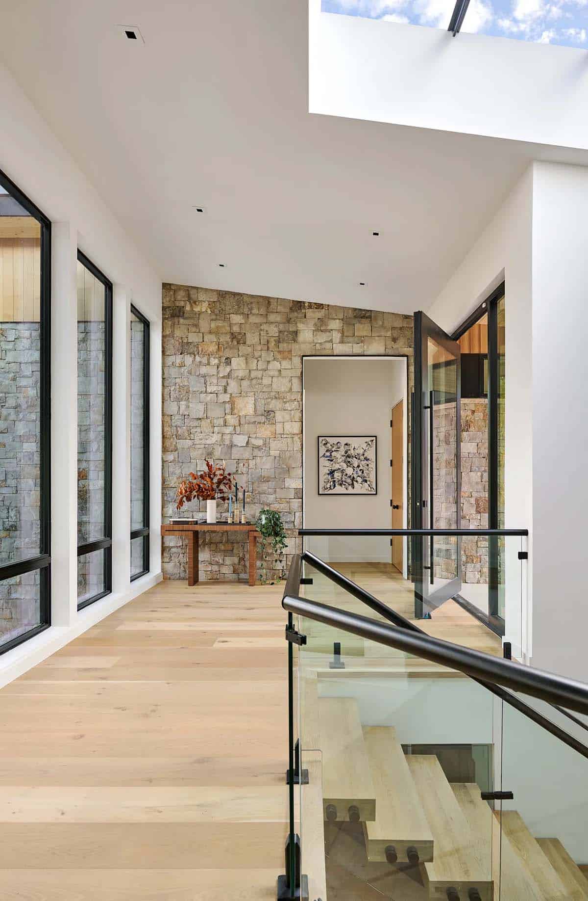 Upper hallway with stacked stone accent wall and skylight