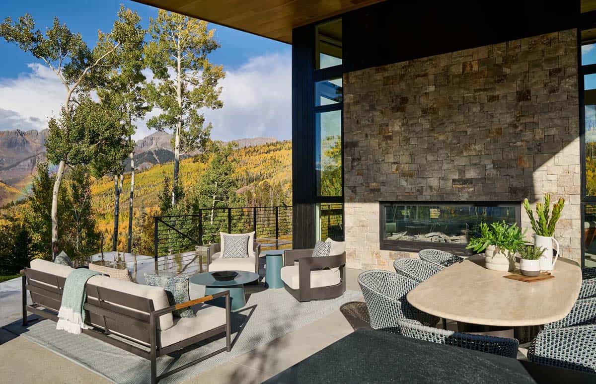 Covered patio with stone fireplace overlooking golden aspen hillside