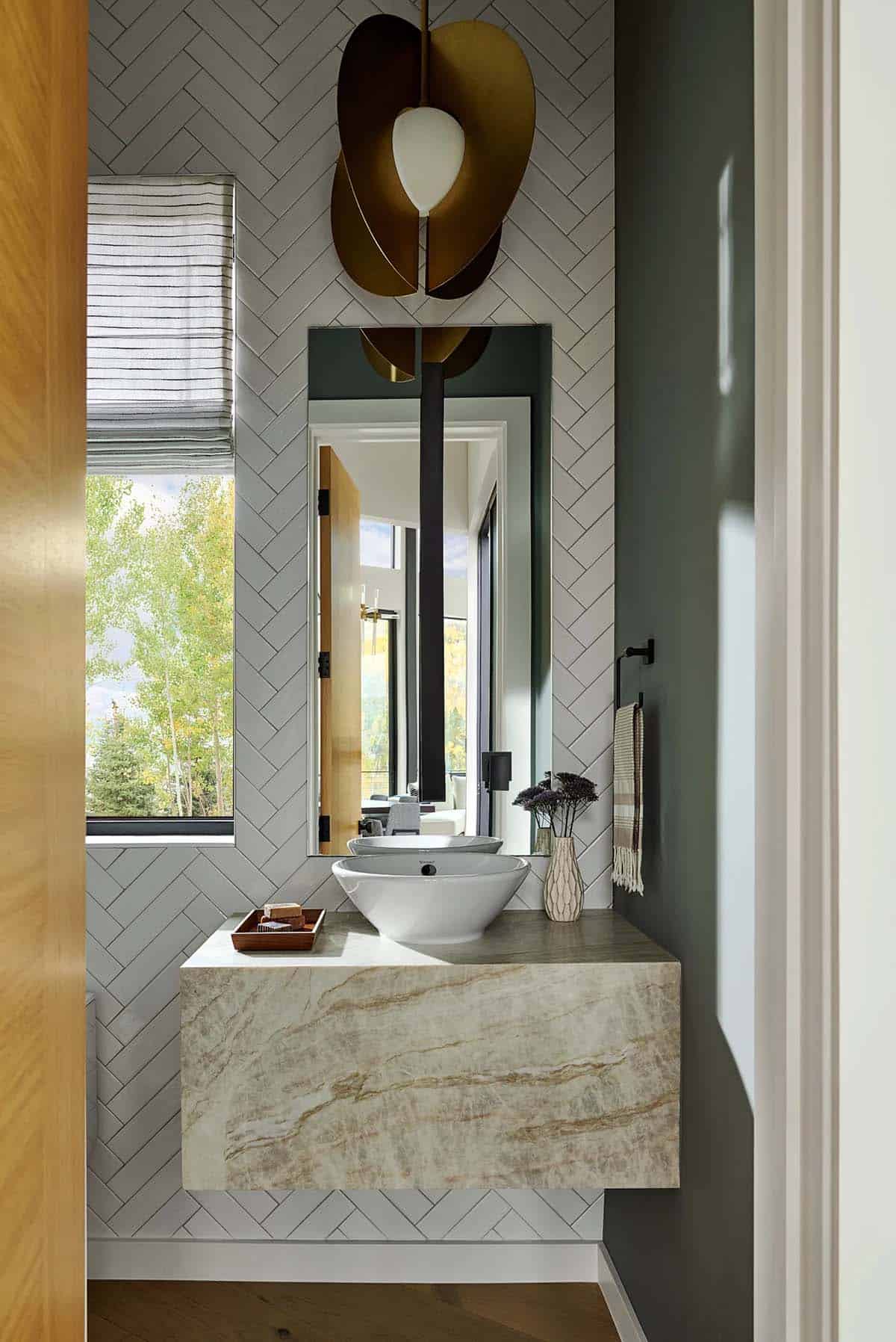 Powder room with herringbone tile and sculptural brass sconce