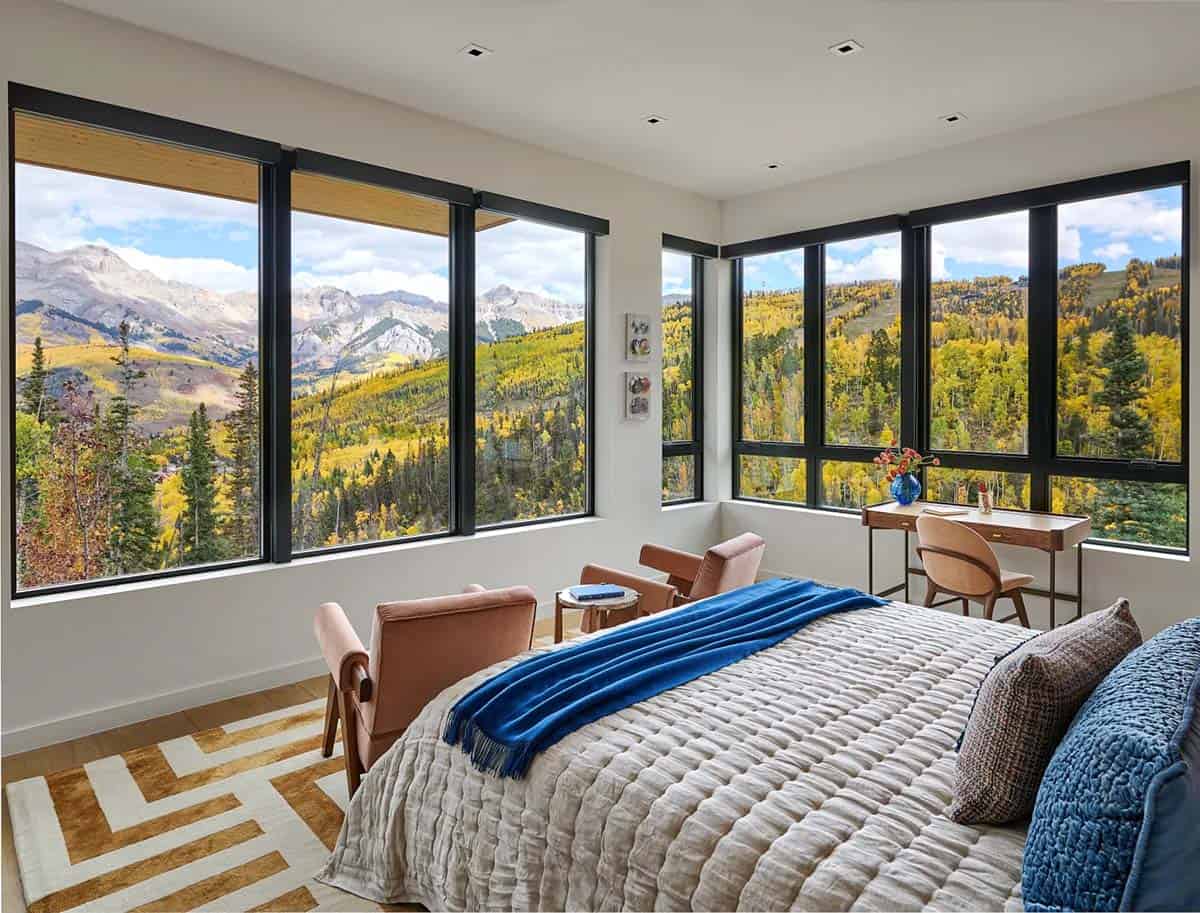 Bedroom corner with wraparound windows framing mountain scenery