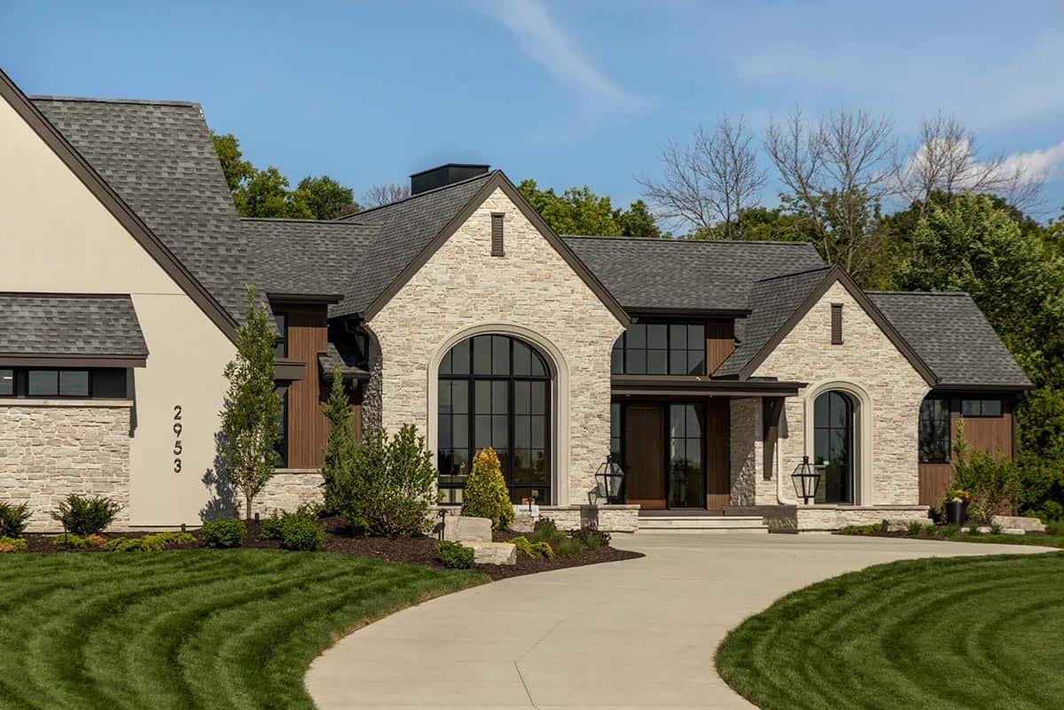 Arched black-framed windows and curved concrete driveway at rambler home front entry