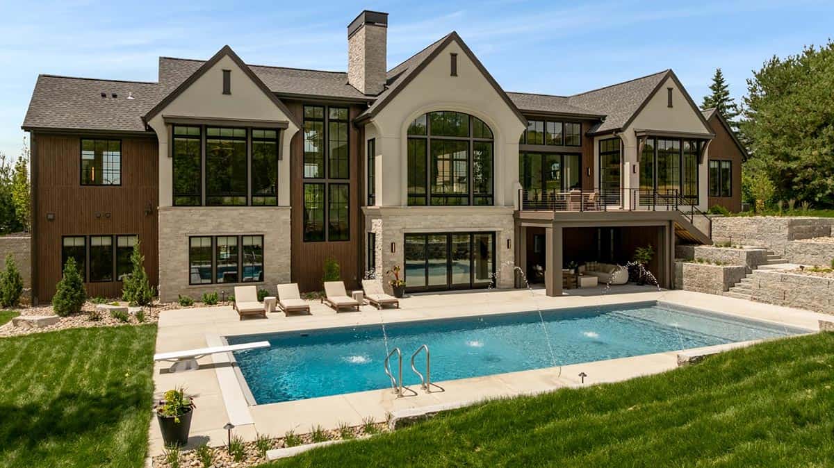 Rear of home with swimming pool, lounge chairs, and stone retaining walls