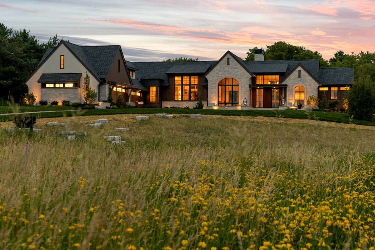 Illuminated stone and wood rambler home at dusk with pink sky