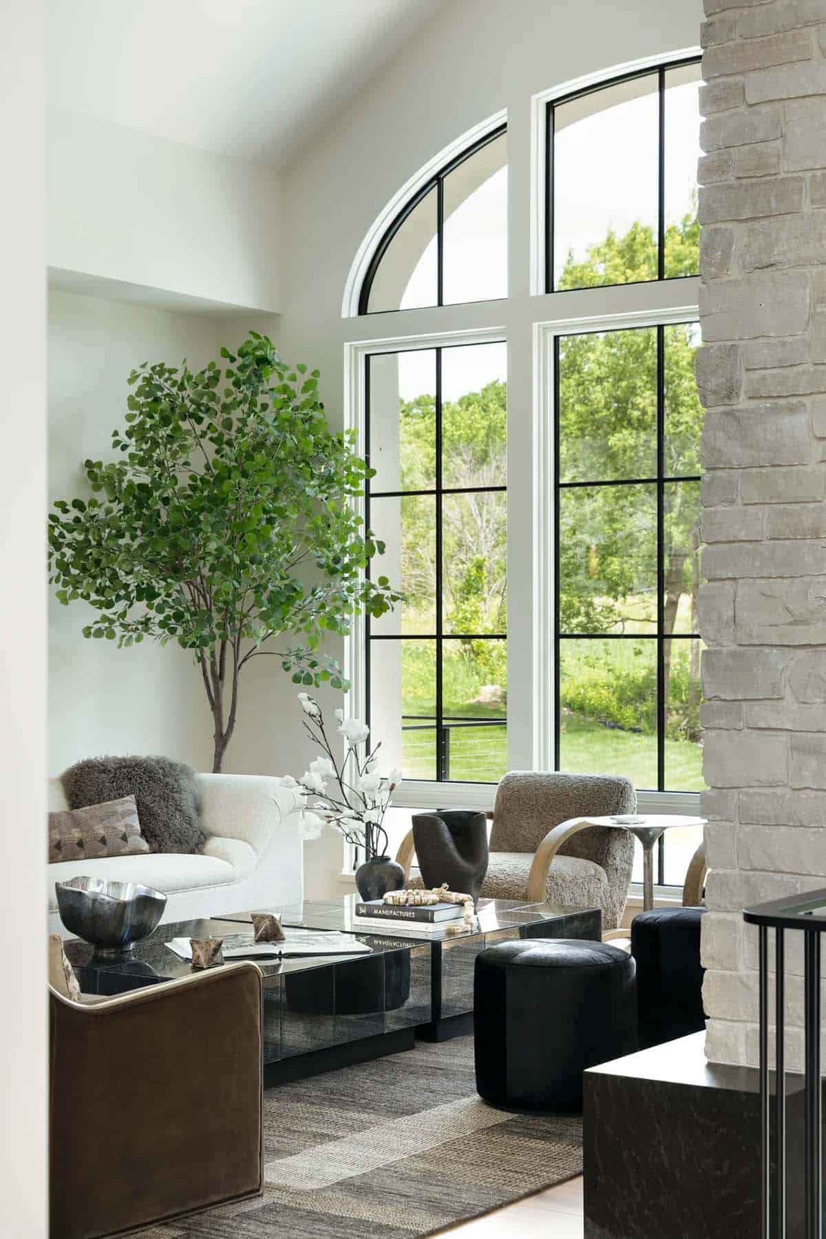 Living room corner with arched windows, indoor tree, and mirrored coffee table