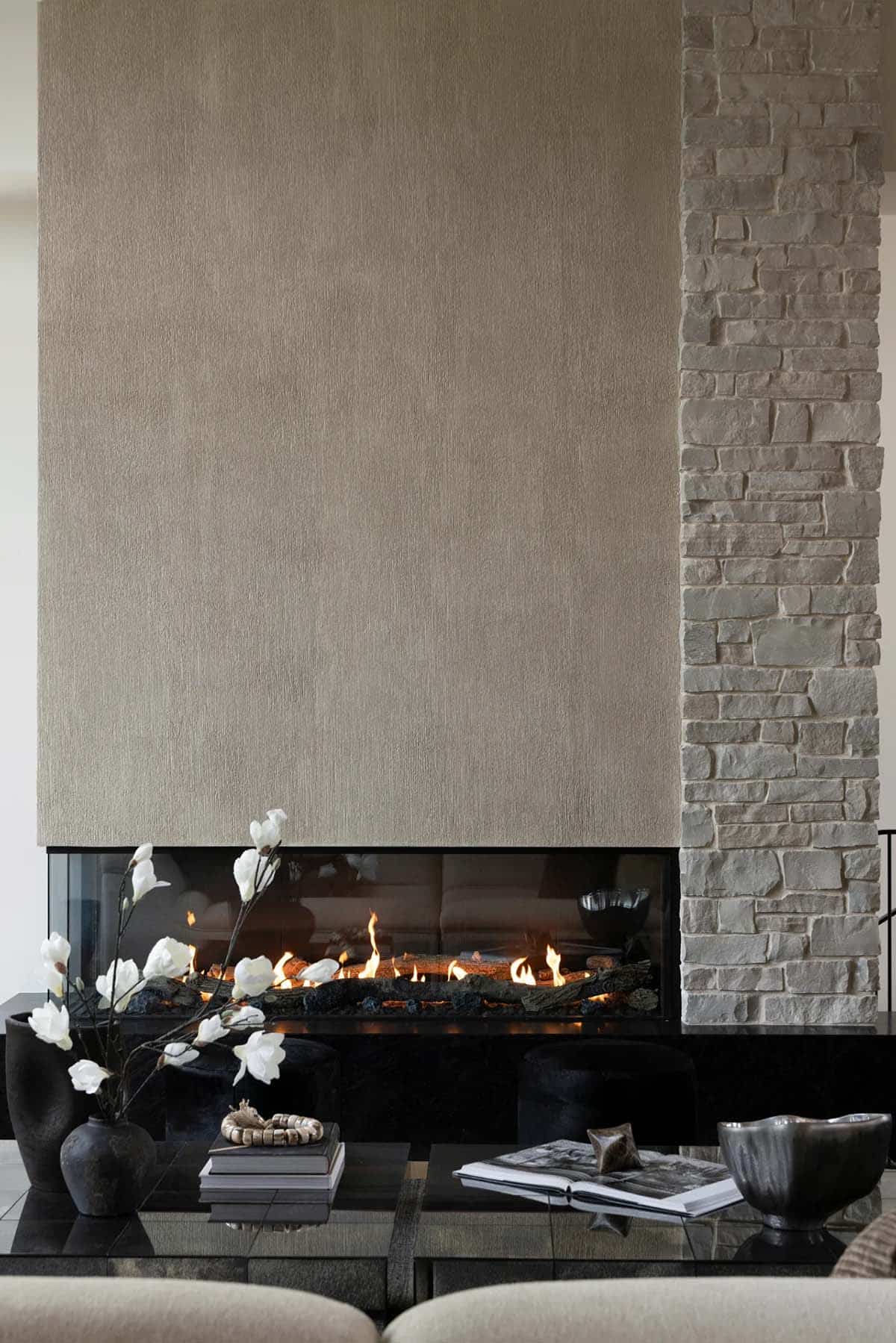 Close view of gas fireplace with textured wall and white magnolia branches
