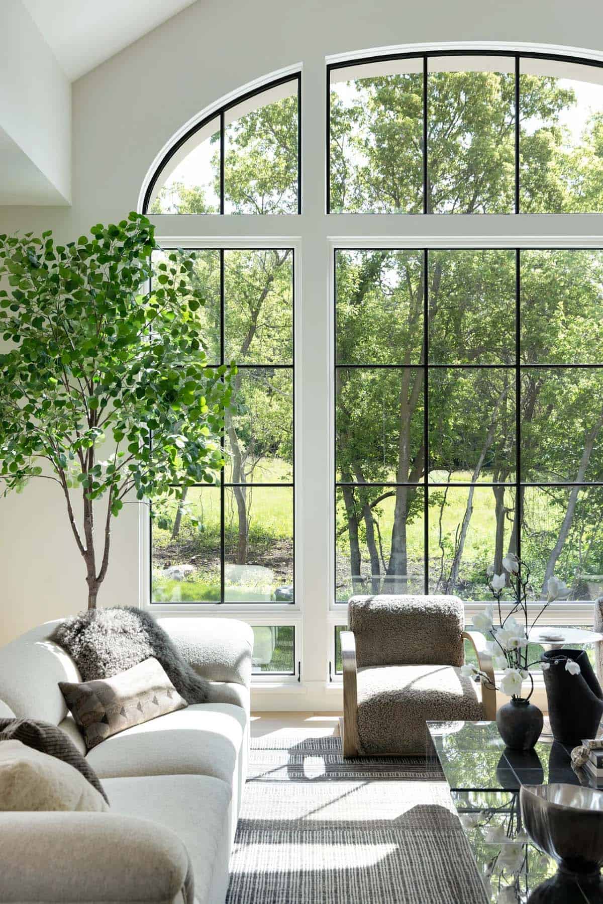Sunlit arched windows with tree views behind shearling chair and sofa