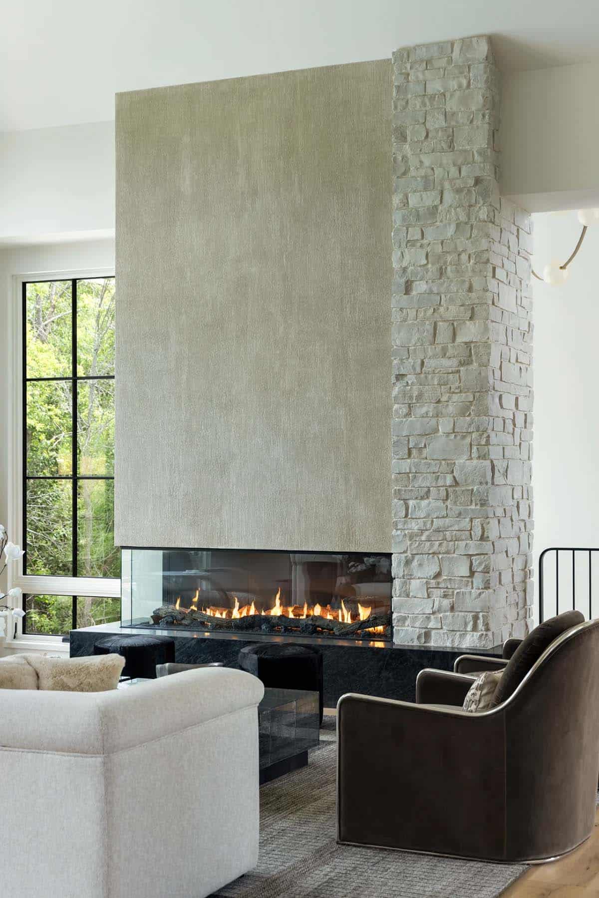 Linear gas fireplace with textured surround, stone column, and velvet swivel chair