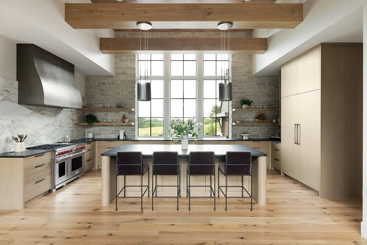 Kitchen with oak beams, stone wall, island seating, and steel range hood
