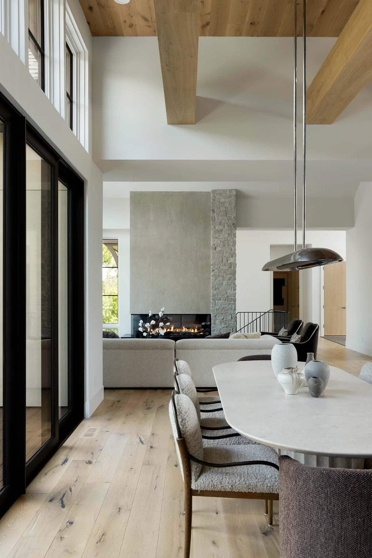 Oval dining table with sculptural pendant and fireplace in the background