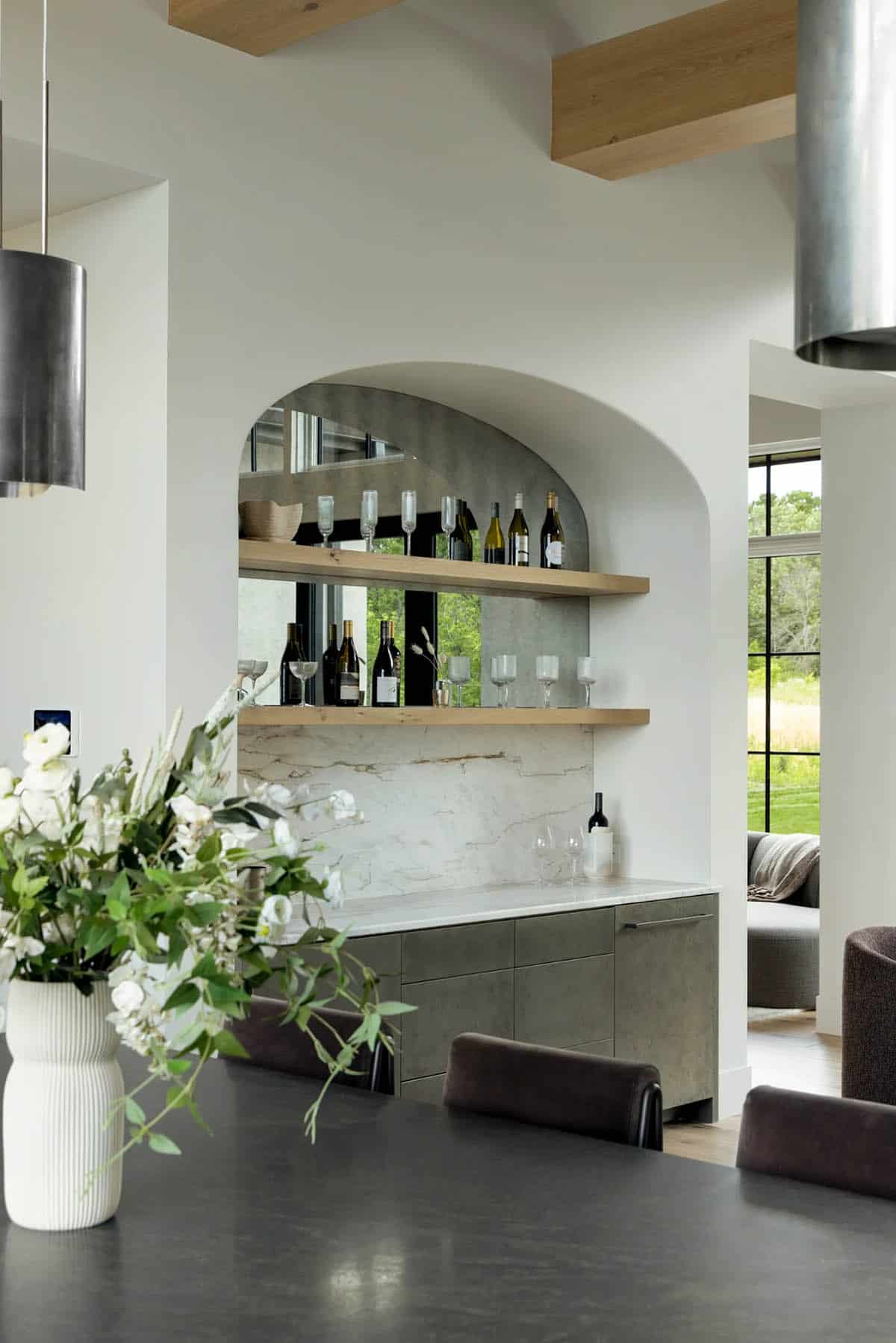 Arched mirrored wine nook with marble backsplash seen across the dark island