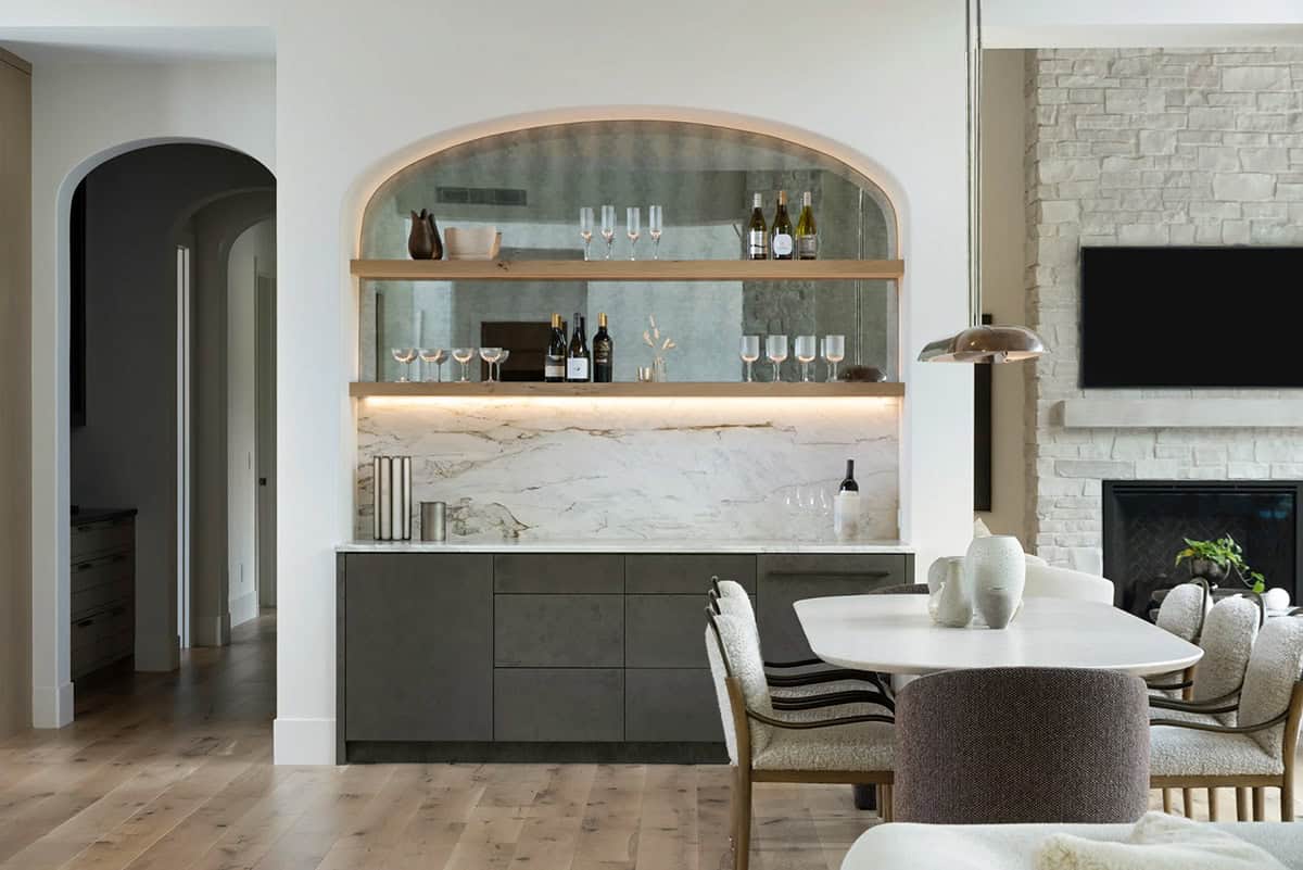 Lit arched bar nook beside dining table and stone fireplace