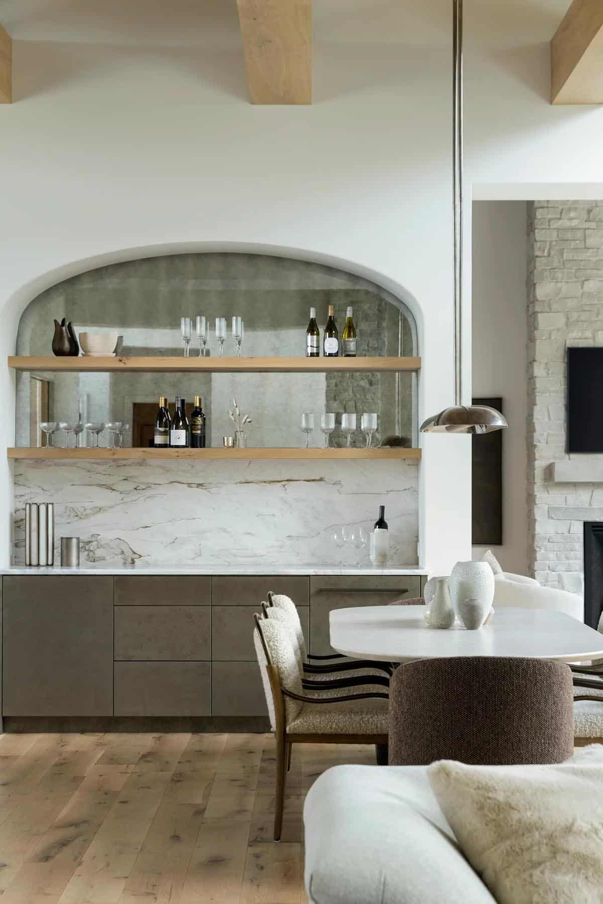 Arched bar nook with mirrored back, oak shelves, and marble backsplash
