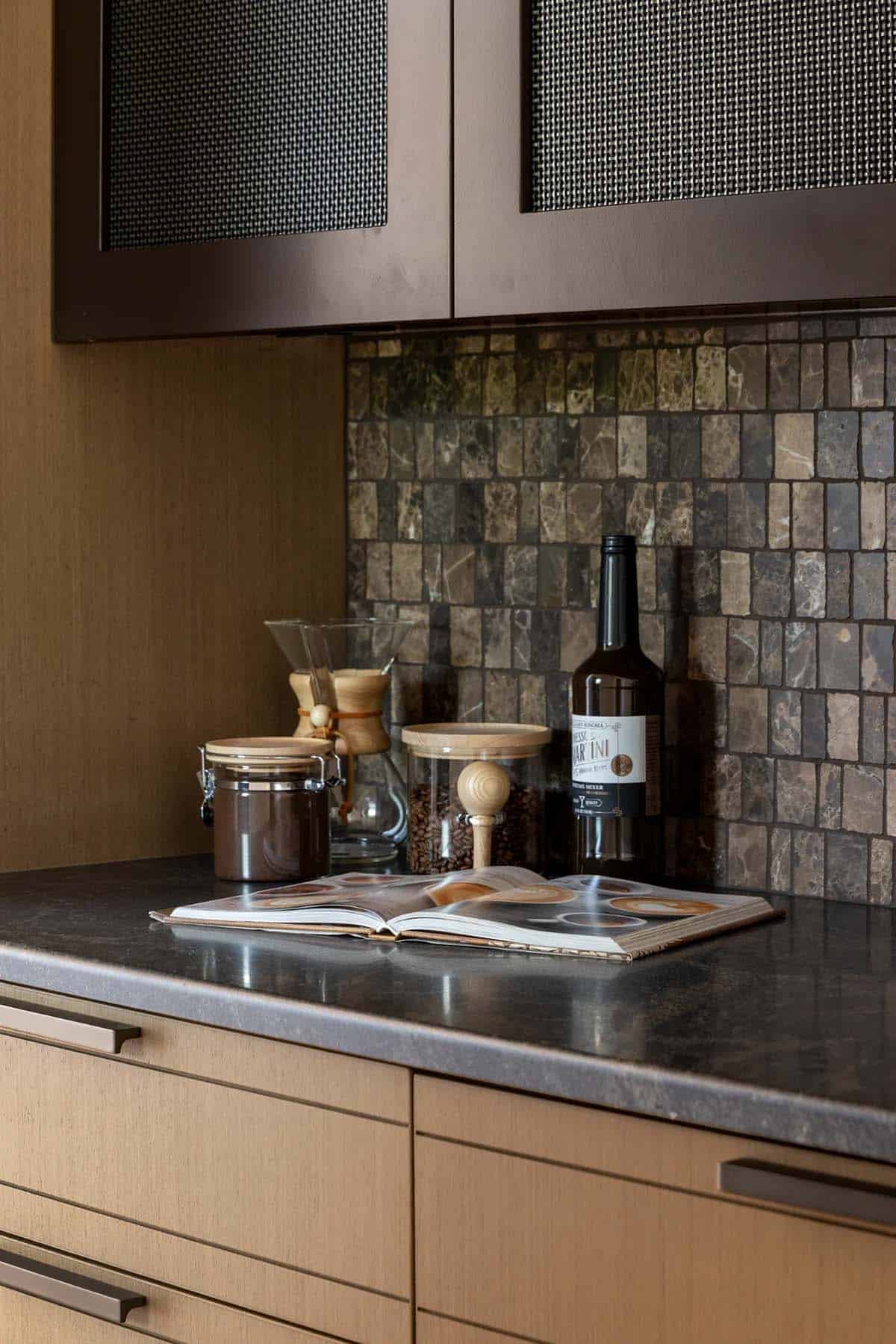Coffee station with mosaic tile backsplash, glass jars, and dark stone counter