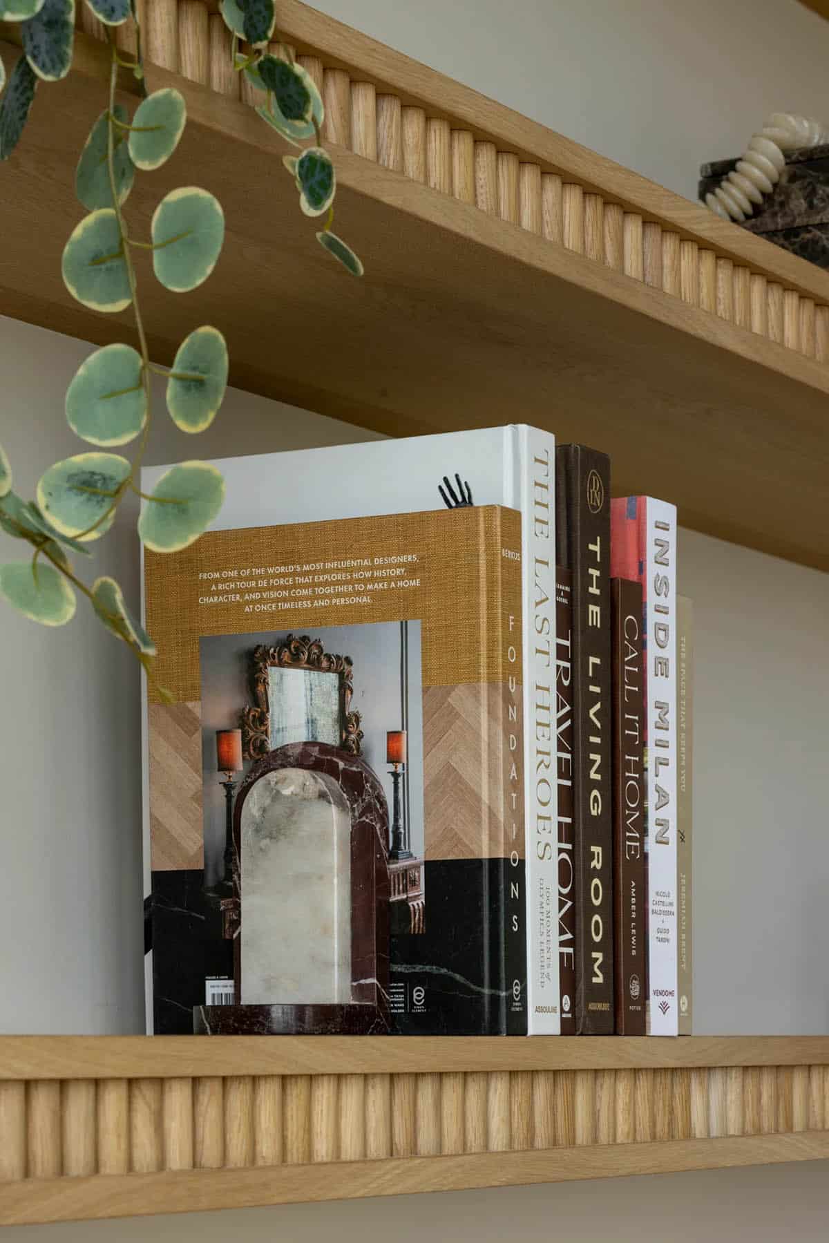 Fluted oak shelf edge with stacked design books and trailing plant