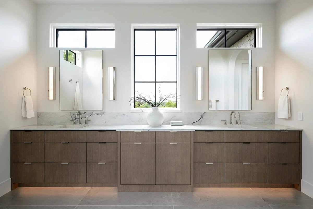 Lit wall sconces and warm toe-kick lighting at double vanity
