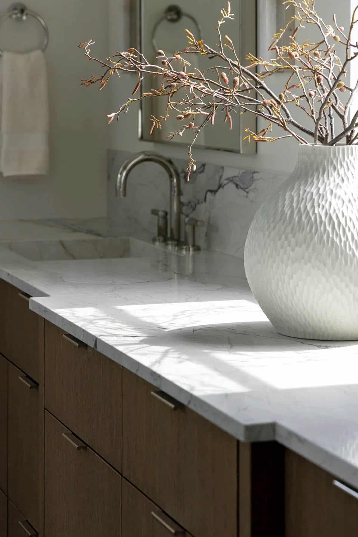 Marble vanity top with polished nickel faucet and textured white vase