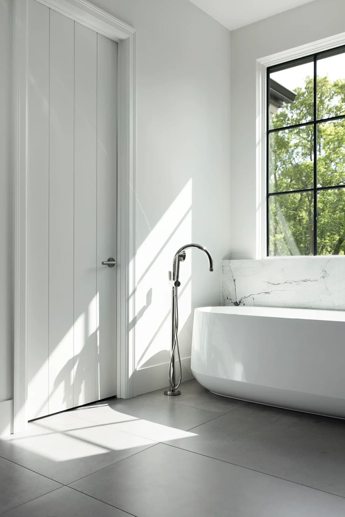 Freestanding tub with floor-mounted faucet beside paneled white door