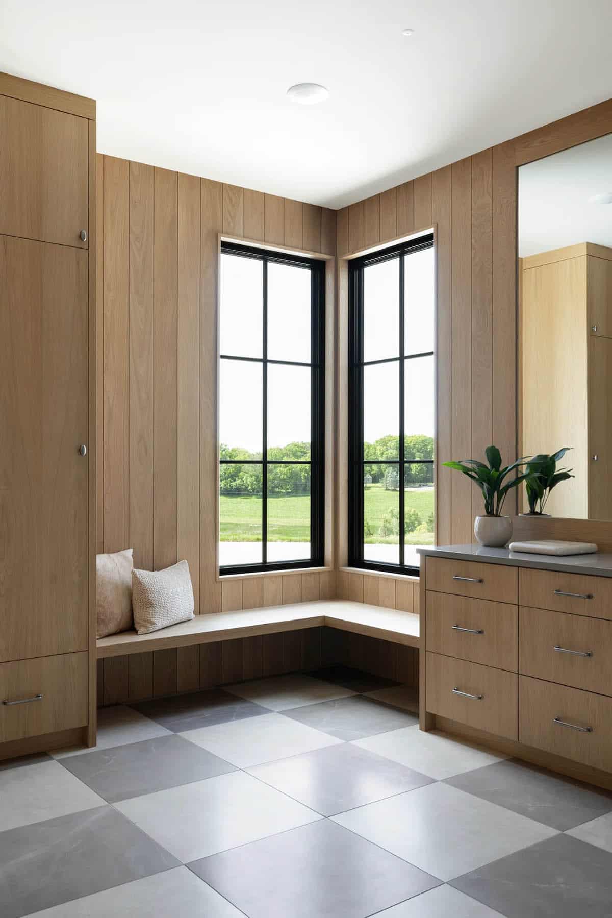 Mudroom with oak paneling, corner window bench, and checkerboard stone floor