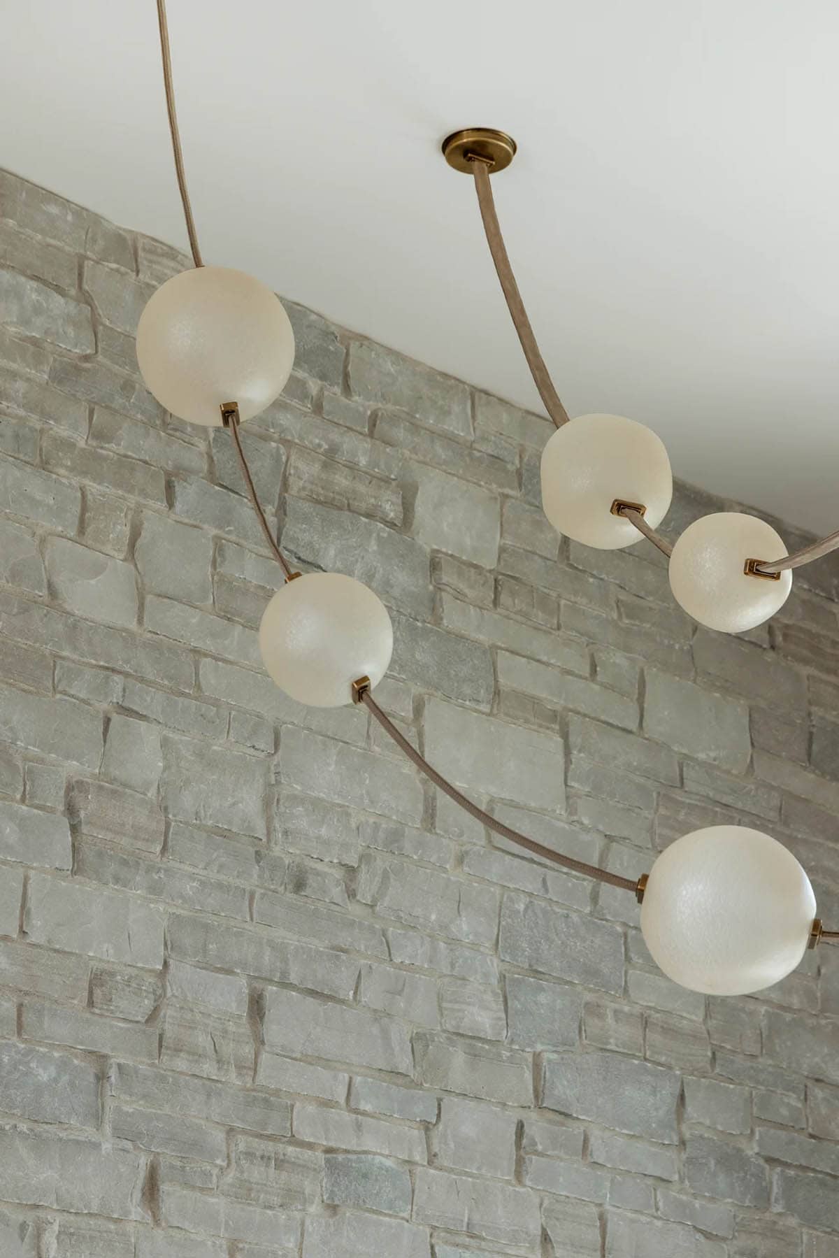 Frosted glass globe chandelier hanging against a gray stone wall