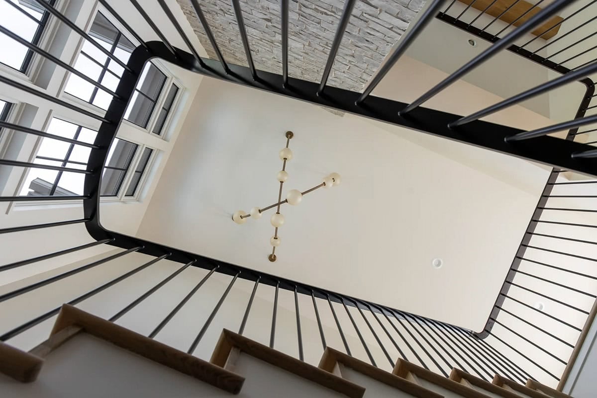 Overhead view of stairwell with black railing and globe chandelier
