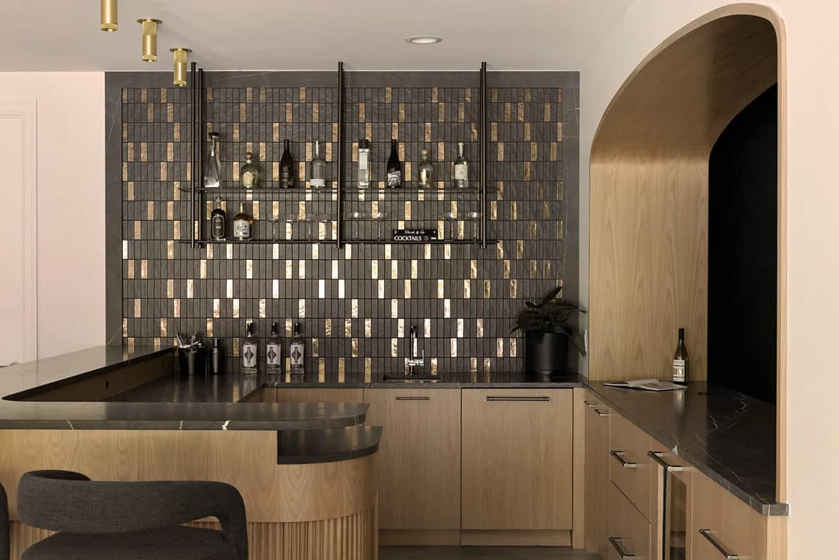 Dark tile backsplash with gold accents behind hanging metal bar shelves