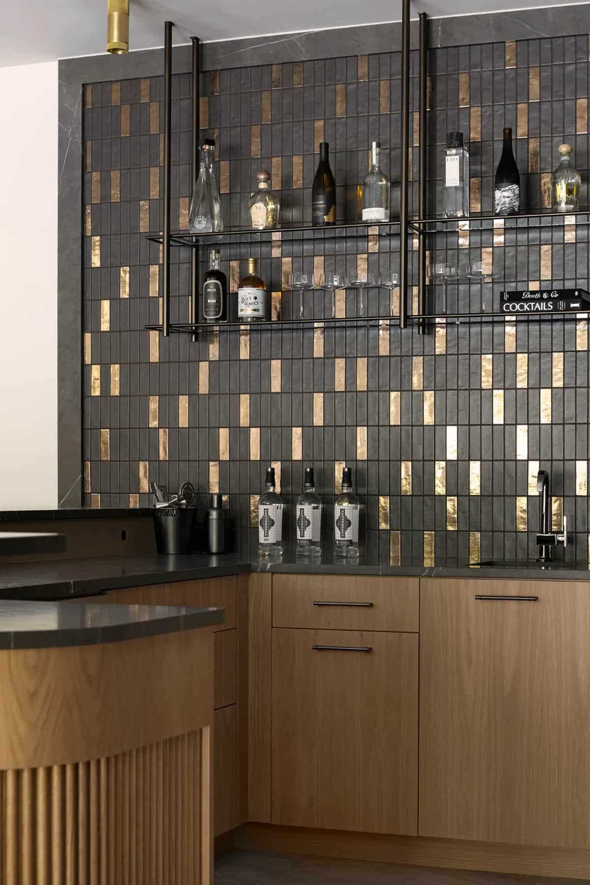 Gold accent tile, glass shelves, and fluted oak bar base