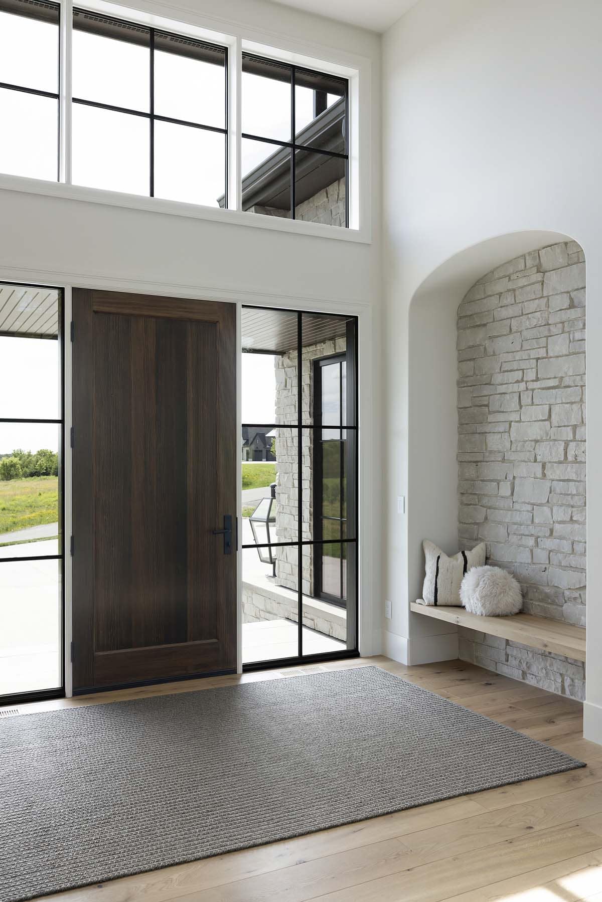 Entryway with wood front door and arched stone bench nook