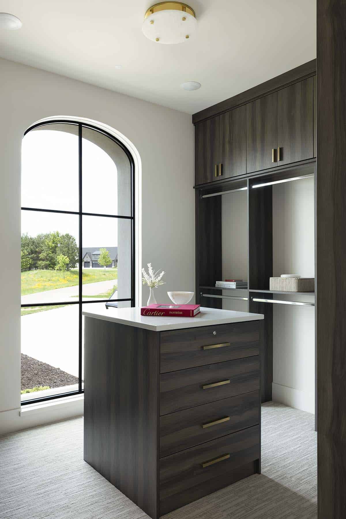 Walk-in closet with dark wood cabinetry, brass hardware, and center island