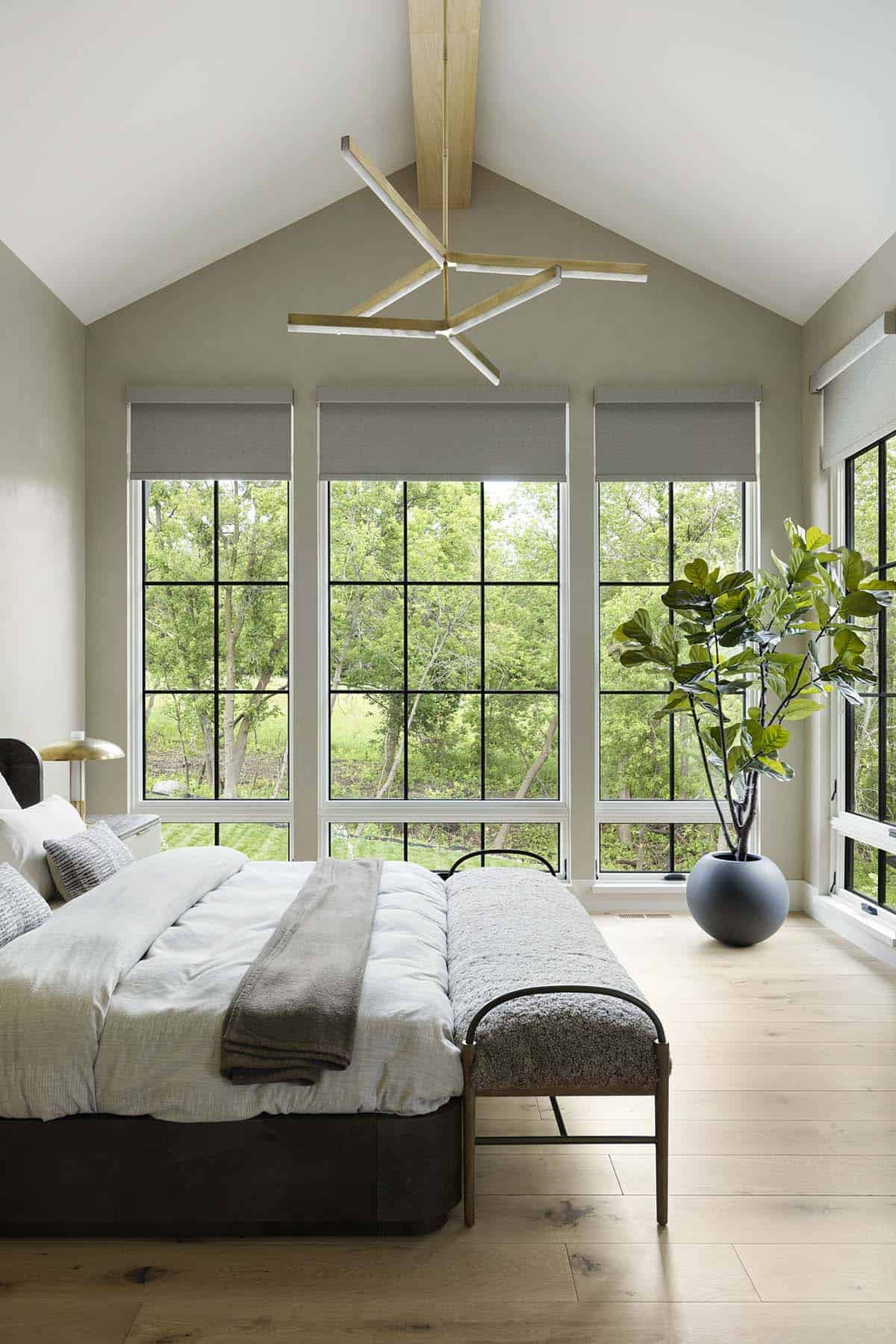 Vaulted bedroom with sculptural light fixture and floor-to-ceiling windows