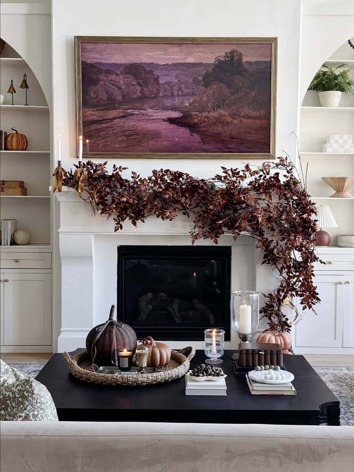 Fireplace mantel draped with a trailing leaf garland and taper candles