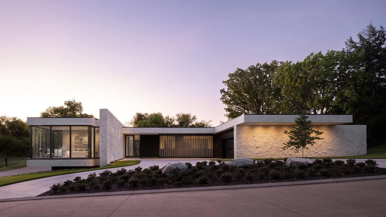 Mid-century modern home exterior with limestone wall at dusk