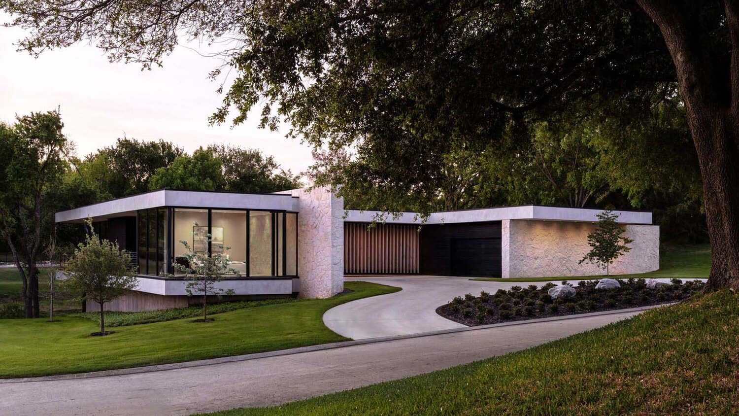 Modern home entry with curved driveway beneath oak trees