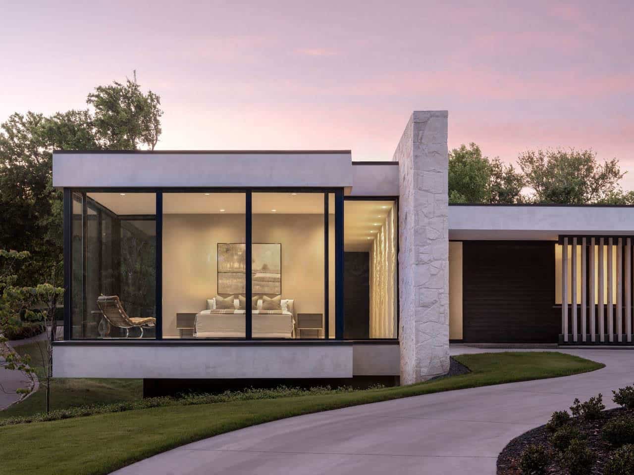Primary bedroom glass wall with stone chimney at sunset