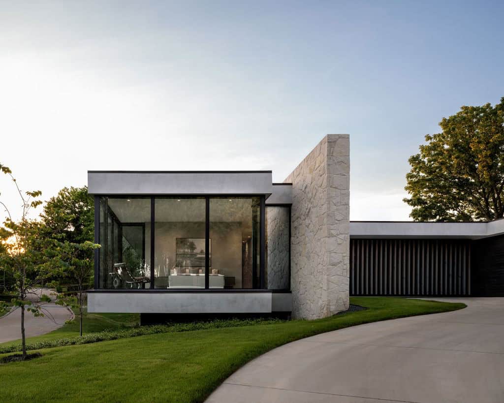 Primary bedroom glass box with limestone chimney at dusk