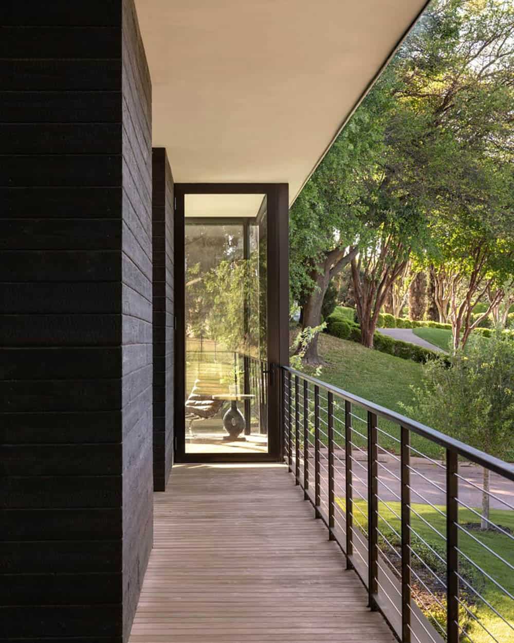 Covered walkway with cable railing overlooking wooded grounds