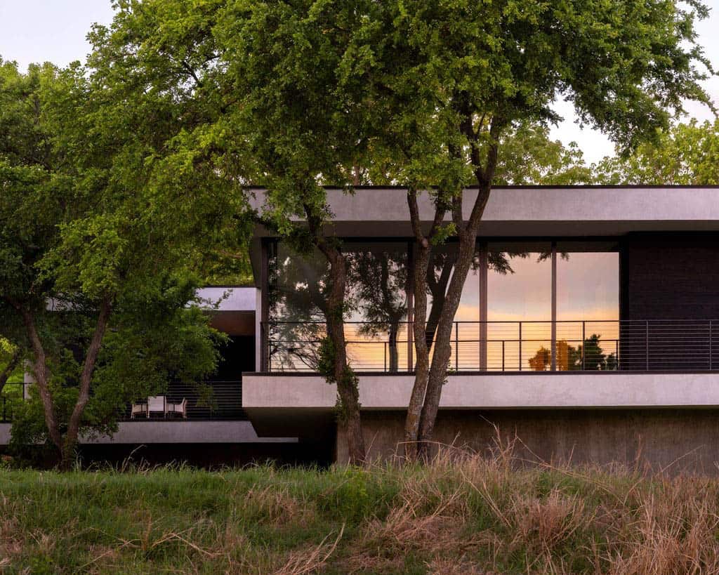 Cantilevered home exterior at dusk with sunset reflection