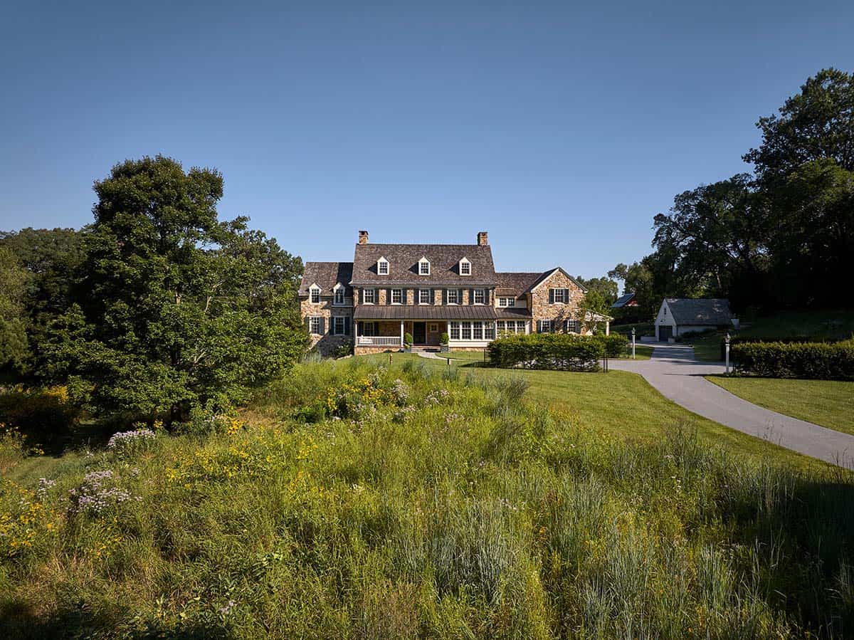 Bucks County stone farmhouse viewed across a wildflower meadow at dusk