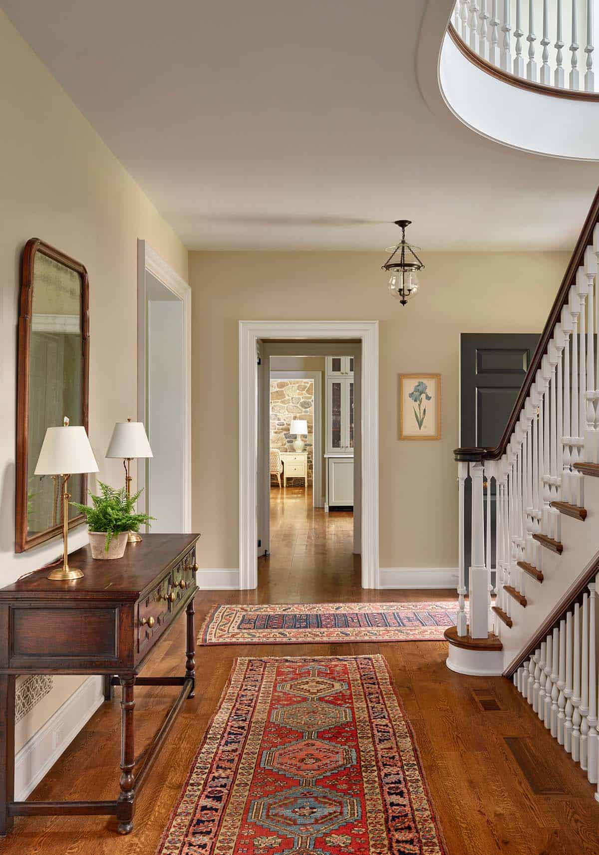 Entry hall with layered vintage rugs and a curved staircase
