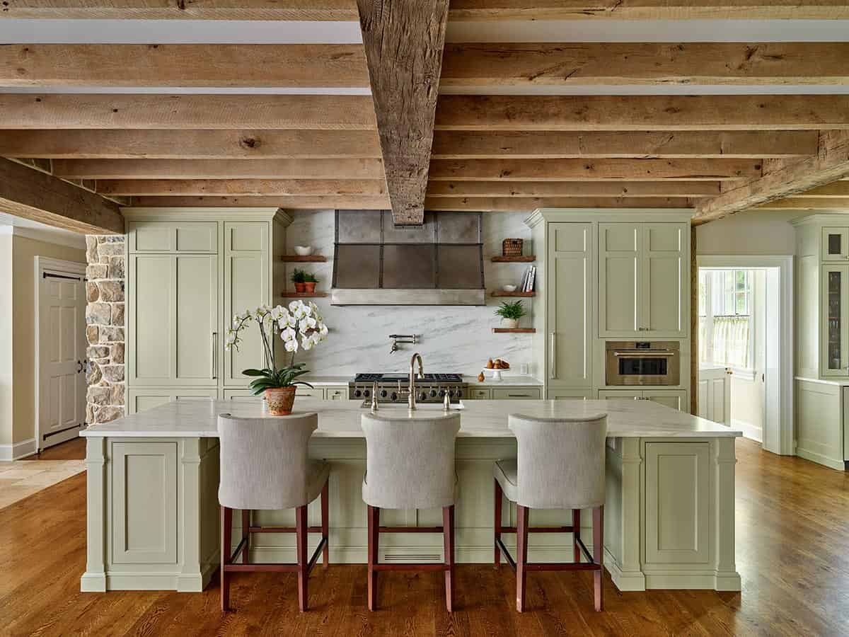 Sage green kitchen island with marble counters and beamed ceiling
