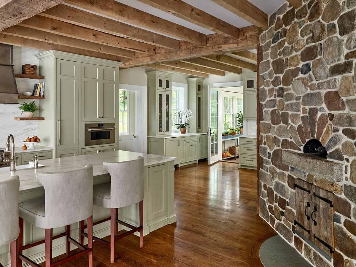 Kitchen with stone wood-fire pizza oven, sage cabinetry, and reclaimed wood beams