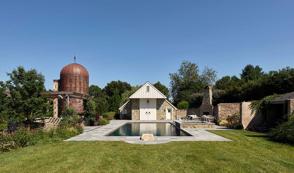 Pool and stone pool house framed by a restored copper silo
