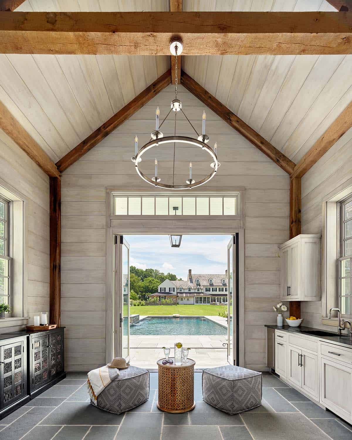 Pool house interior with vaulted ceiling and chandelier overlooking the pool