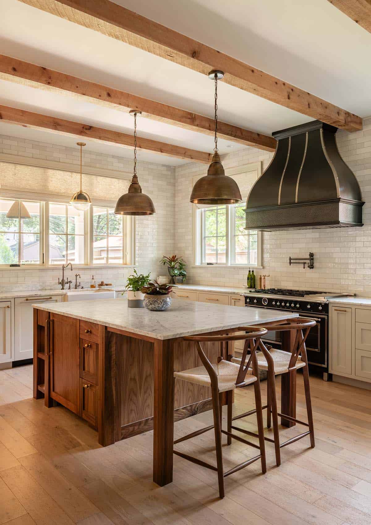 Kitchen island with walnut cabinetry and black vented range hood