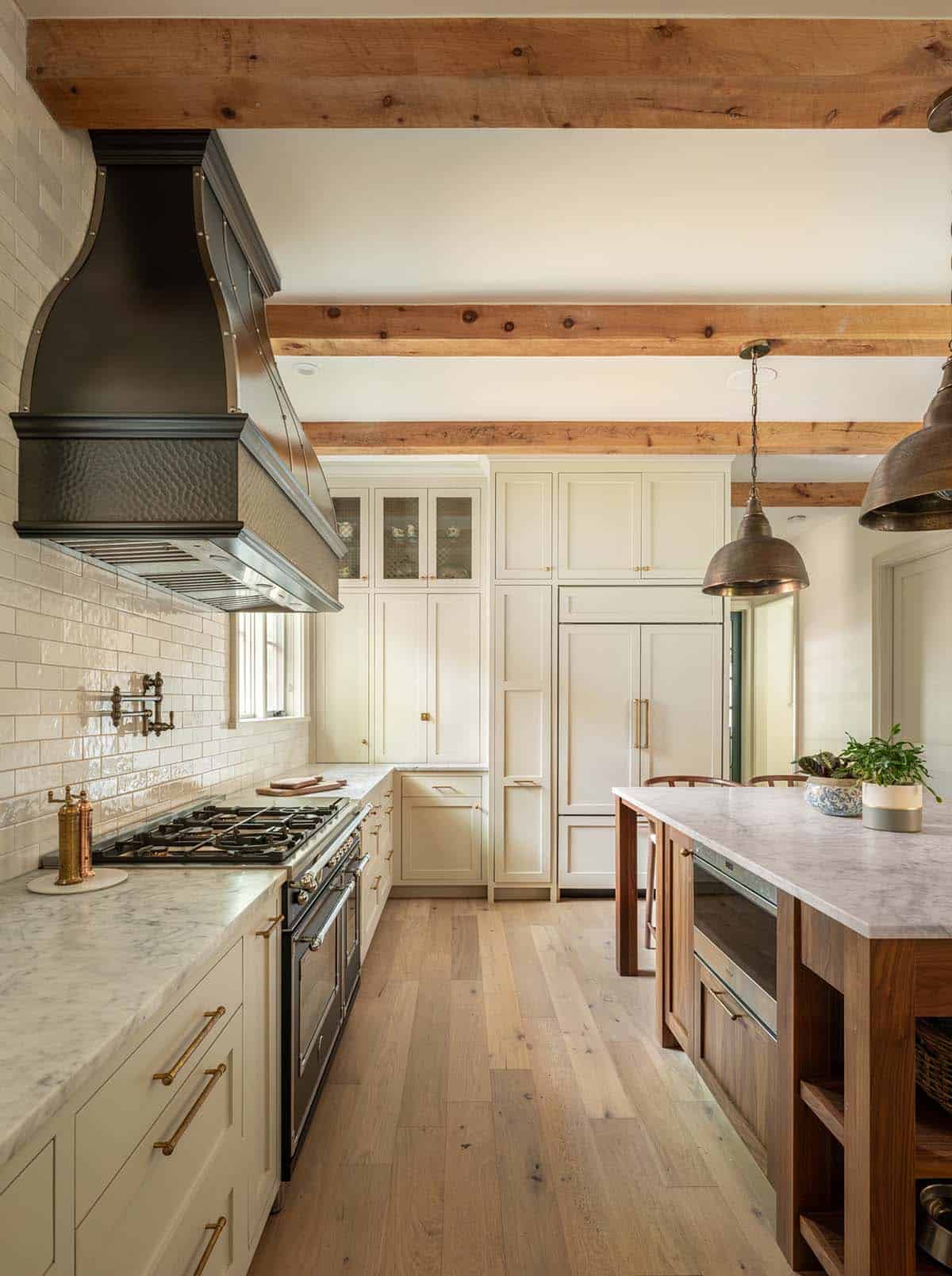 Galley kitchen with brass hood, gas range, and built-in pantry
