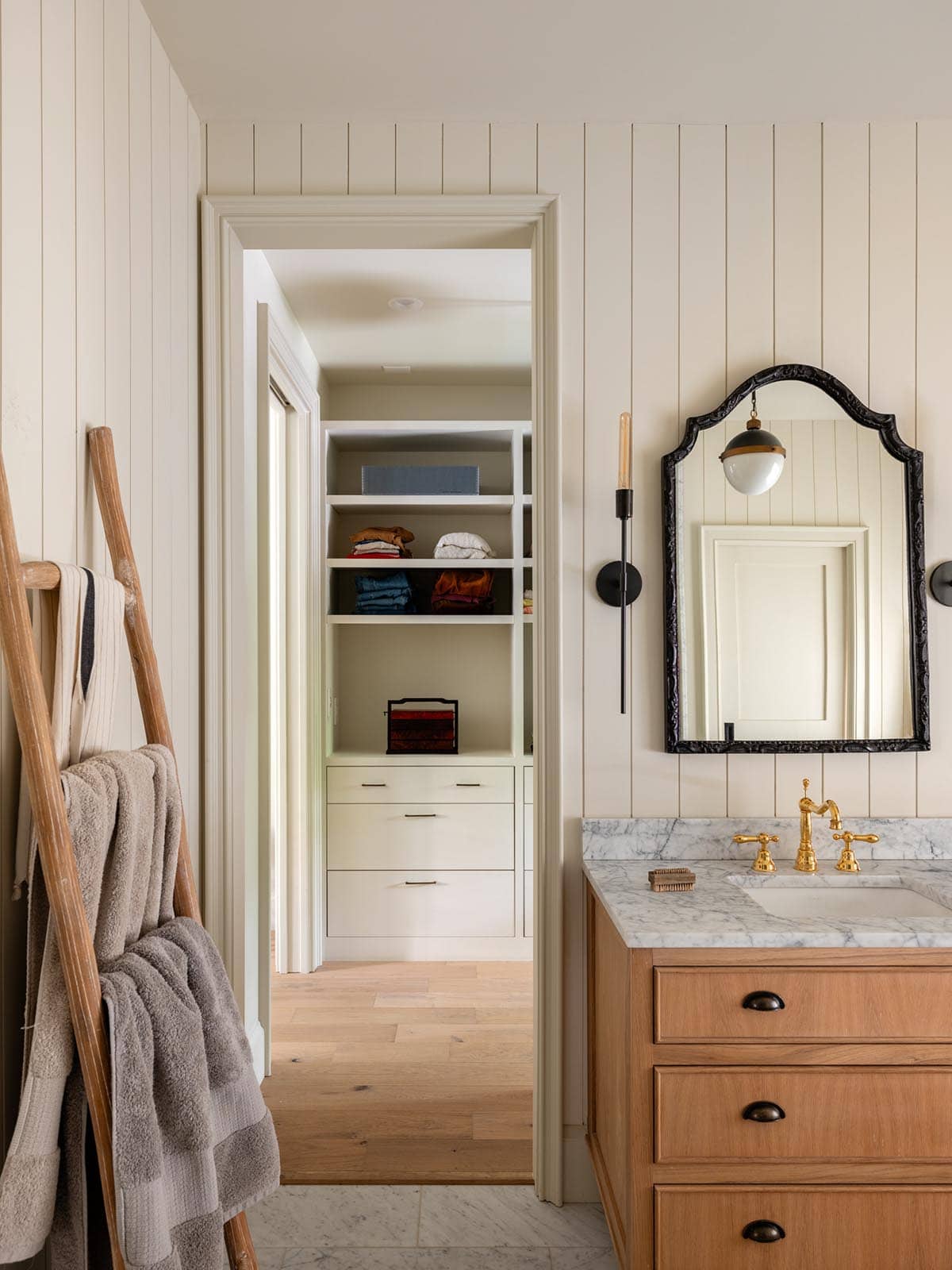 Bathroom vanity with view into walk-in closet and shelving